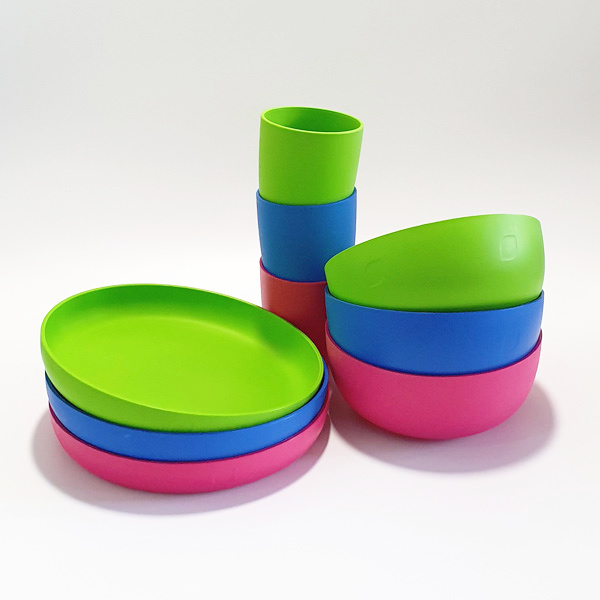 Drei Plastikgeschirr-Sets bestehend aus Teller, Schälchen und Becher in Blau,Pink und Grün auf weißem Hintergrund.